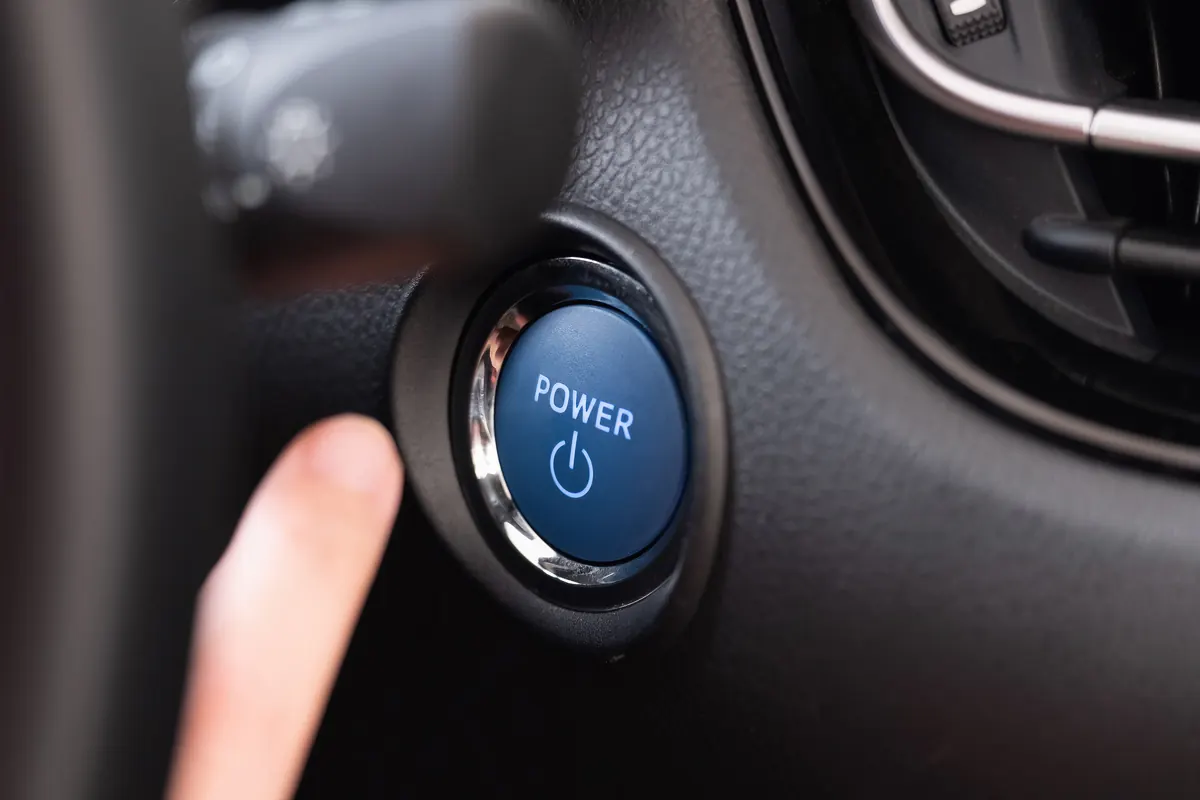 Doigt appuyant sur le bouton POWER d’une voiture hybride