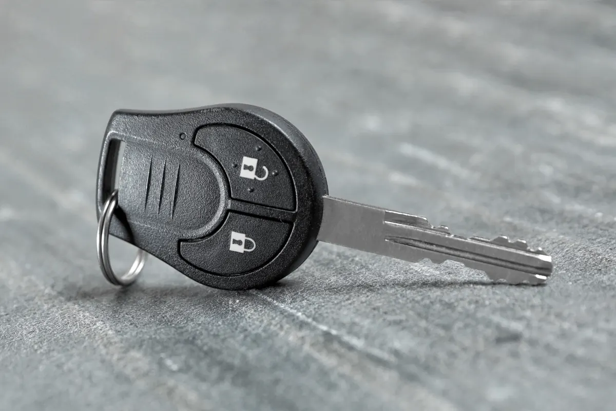 Clé télécommande à deux boutons et lame fixe posée sur une surface grise