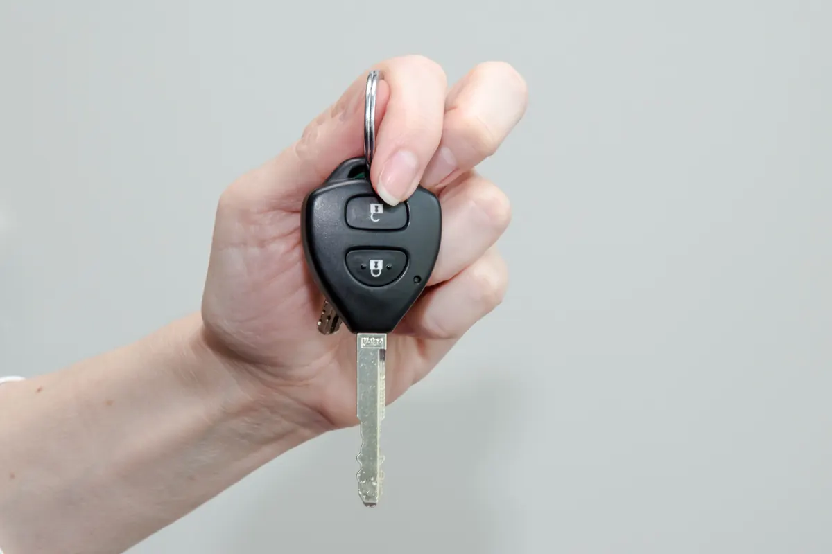 Clé télécommande à deux boutons et lame fixe tenue dans la main