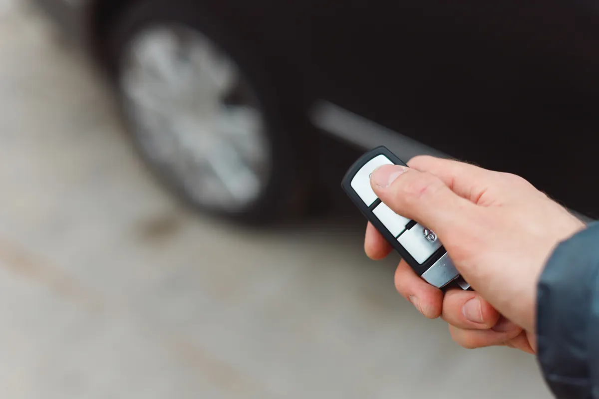 Main appuyant sur la télécommande d’une clé de voiture