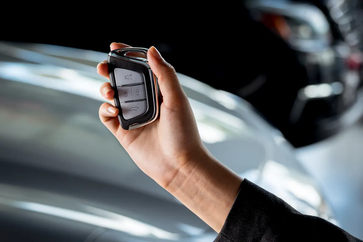 Main tenant une smart key devant une voiture