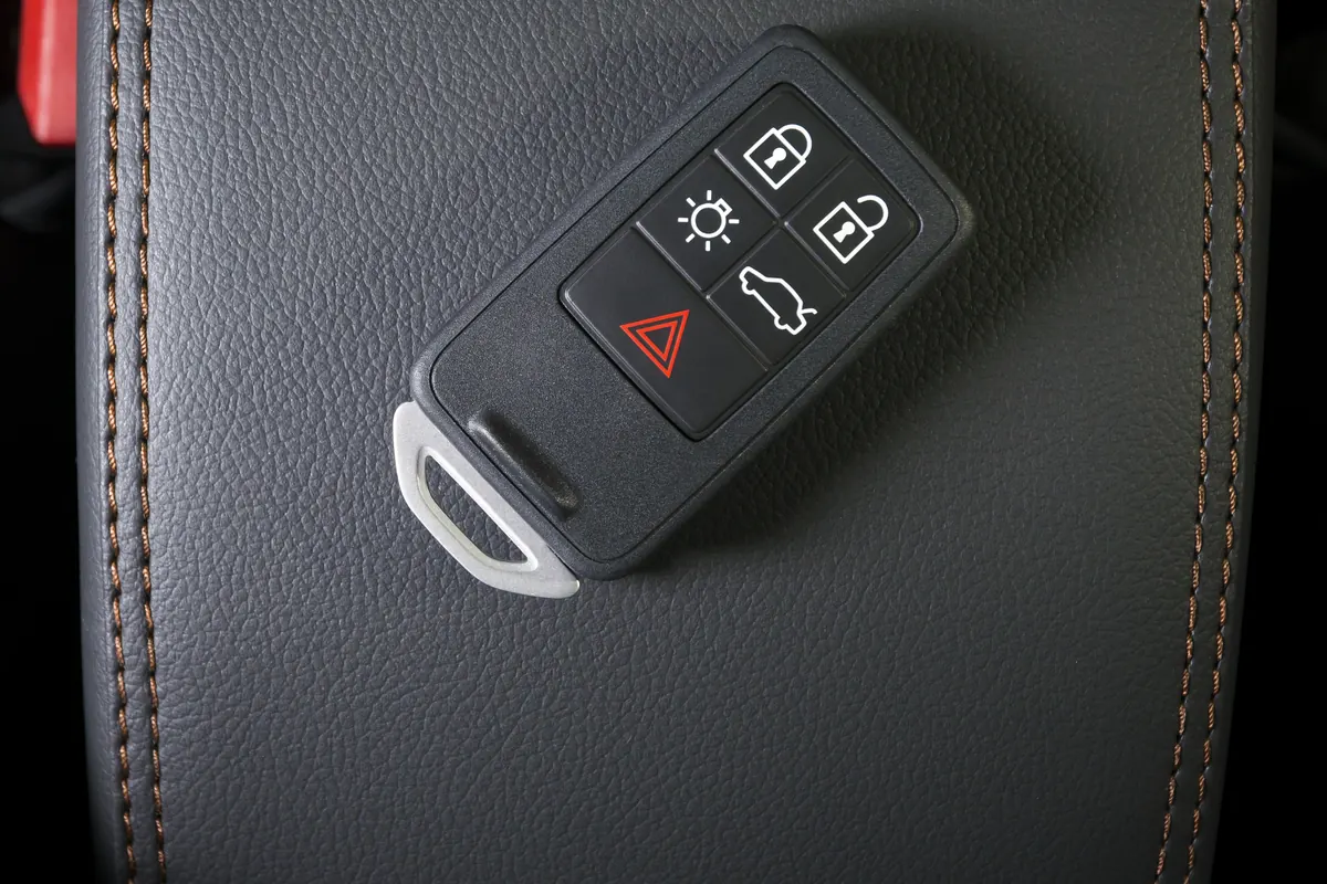 Télécommande de clé Volvo à cinq boutons posée sur un accoudoir en cuir